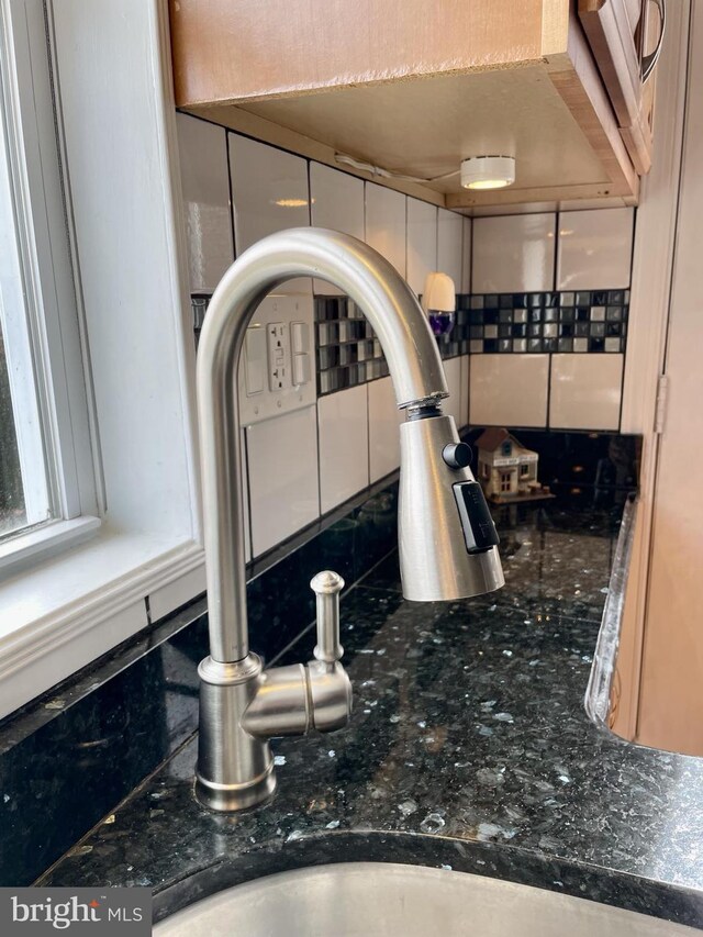 interior details featuring dark stone counters, tasteful backsplash, and a sink