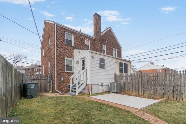 rear view of house with brick siding, a lawn, entry steps, a patio area, and central AC