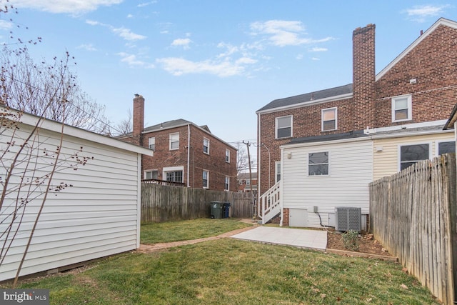 rear view of property featuring a yard, a fenced backyard, a patio, and brick siding