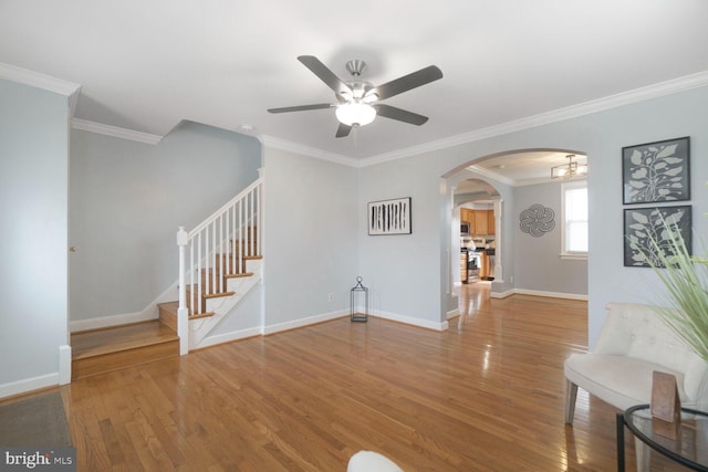 unfurnished living room featuring arched walkways, wood finished floors, stairs, and baseboards