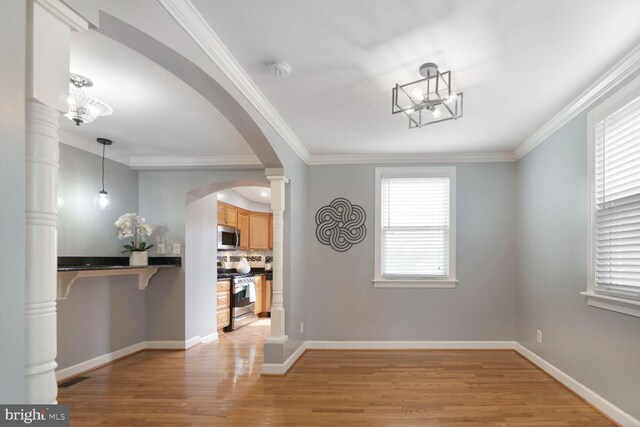 unfurnished dining area featuring light wood finished floors, visible vents, arched walkways, and ornamental molding