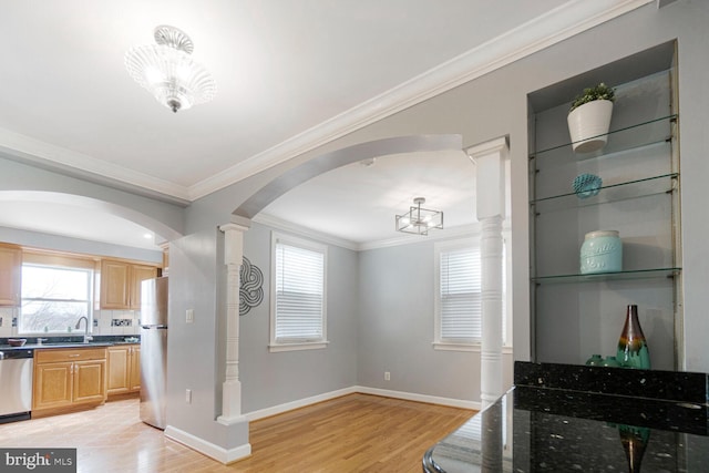 kitchen with arched walkways, stainless steel dishwasher, light wood-style floors, freestanding refrigerator, and a sink