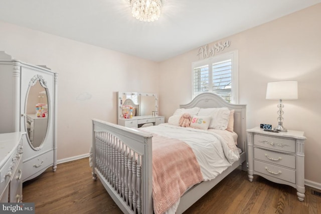 bedroom with dark wood-type flooring, a chandelier, visible vents, and baseboards