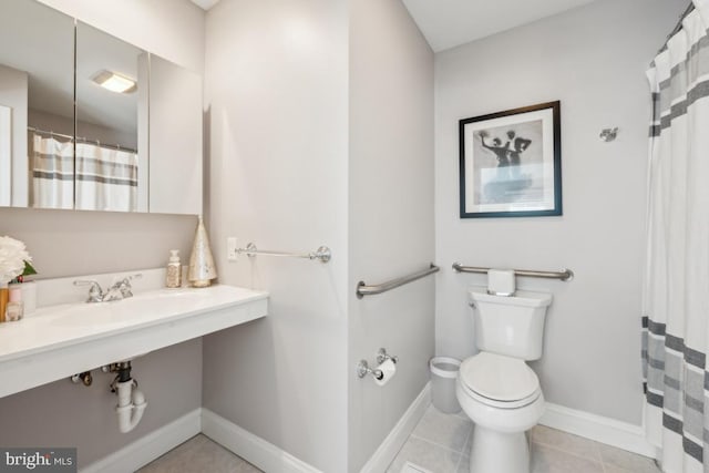 bathroom with toilet, curtained shower, tile patterned flooring, and baseboards