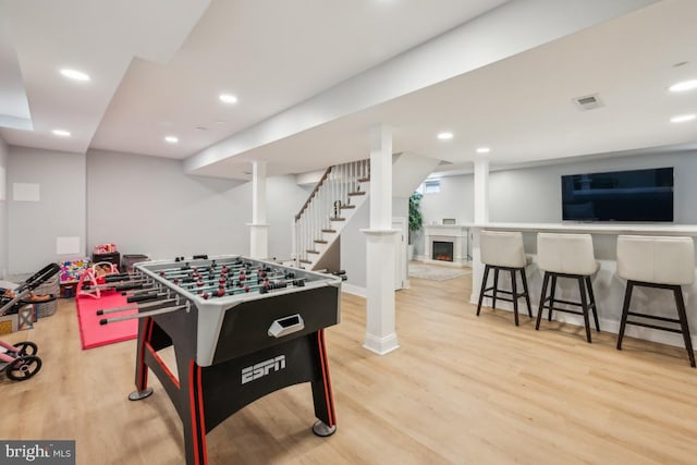 recreation room featuring a lit fireplace, light wood-type flooring, visible vents, and recessed lighting