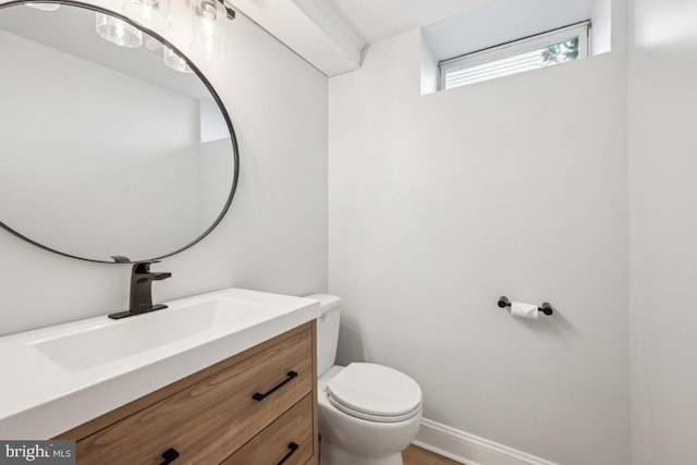 bathroom with toilet, baseboards, and vanity