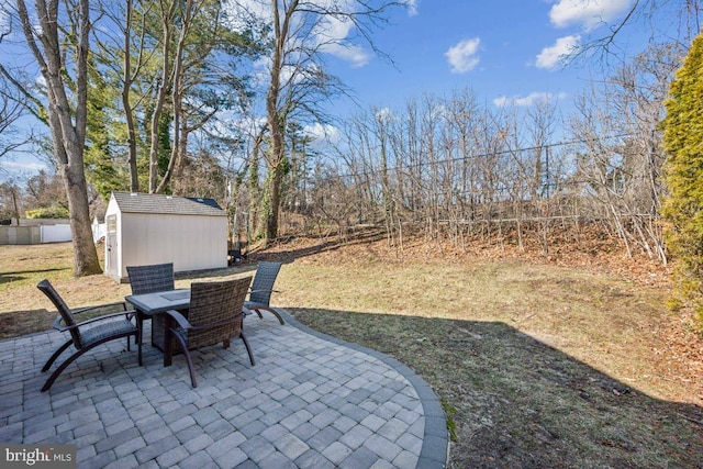 view of patio with a storage shed, fence, outdoor dining area, and an outdoor structure