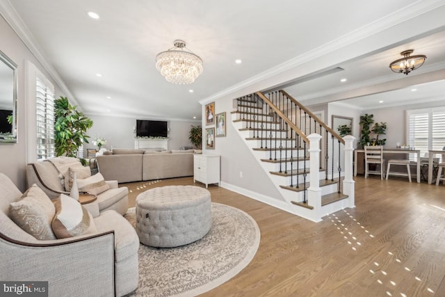 living room with ornamental molding, wood finished floors, stairs, a chandelier, and recessed lighting