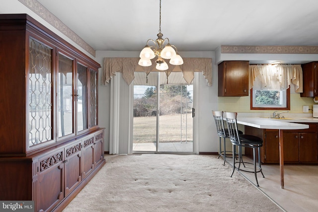 dining area featuring an inviting chandelier, light colored carpet, and sink