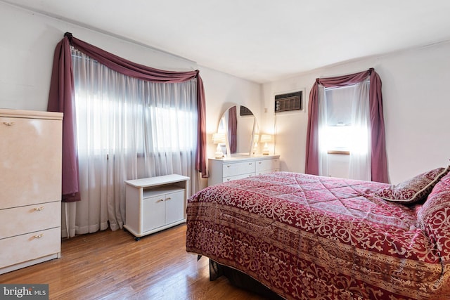 bedroom with wood-type flooring and an AC wall unit