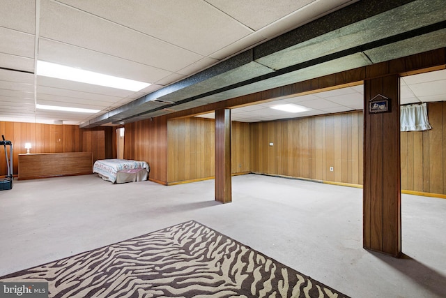 basement with a drop ceiling and wood walls