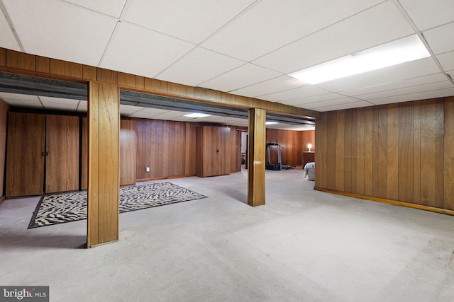 basement with a drop ceiling and wooden walls