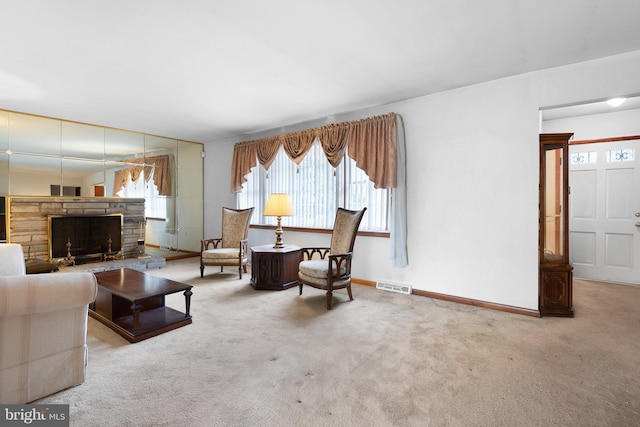 carpeted living room with a stone fireplace