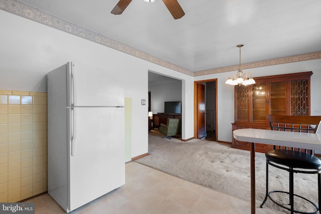 dining space featuring tile walls, ceiling fan with notable chandelier, and light colored carpet