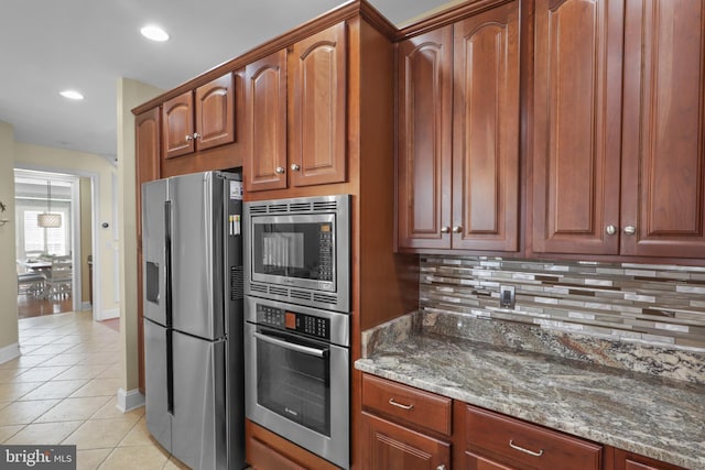 kitchen featuring light tile patterned flooring, appliances with stainless steel finishes, dark stone countertops, and backsplash