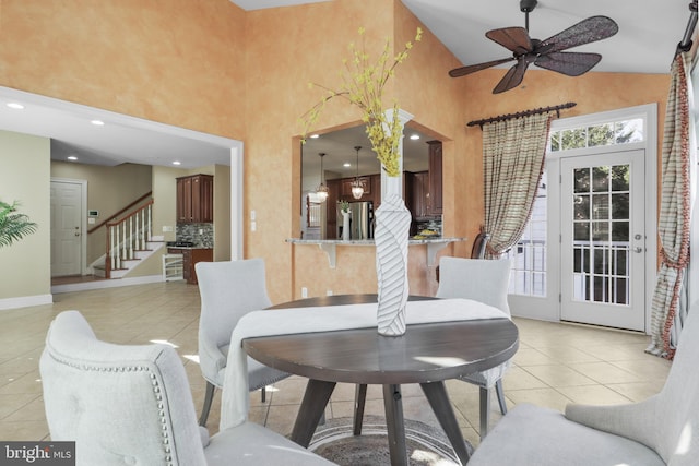 tiled dining room with ceiling fan and high vaulted ceiling