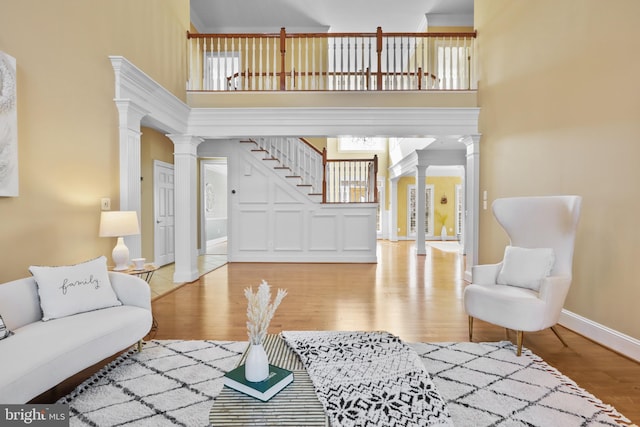 living room featuring decorative columns, a towering ceiling, and hardwood / wood-style floors