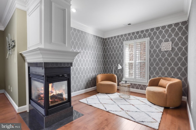 living area featuring ornamental molding, hardwood / wood-style floors, and a multi sided fireplace