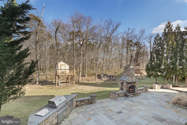 view of patio with exterior kitchen and an outdoor stone fireplace