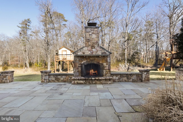 view of patio / terrace featuring a playground and an outdoor stone fireplace