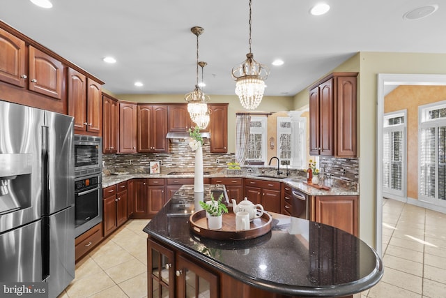 kitchen with sink, dark stone countertops, a center island, light tile patterned floors, and stainless steel appliances