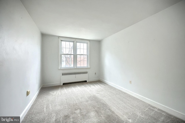 empty room with light colored carpet and radiator heating unit