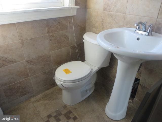 bathroom featuring toilet, tile patterned flooring, and tile walls