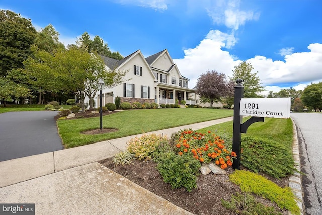 view of front facade featuring stone siding, a front lawn, driveway, and stucco siding