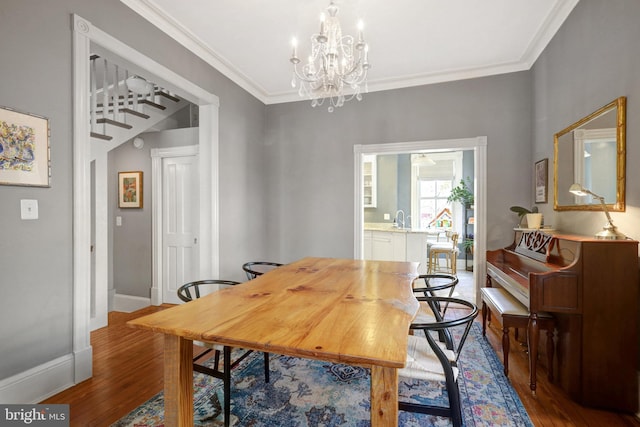 dining area featuring a chandelier, baseboards, wood finished floors, and crown molding