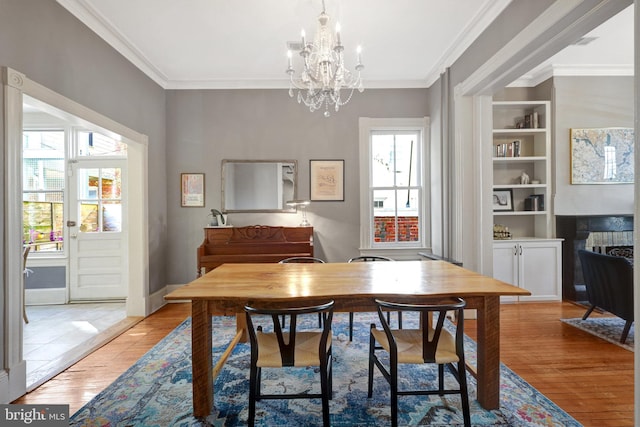 dining space with built in features, light wood-type flooring, and ornamental molding