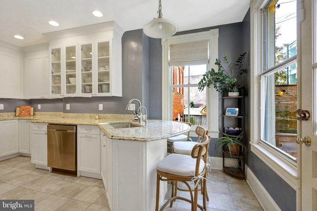 kitchen with a breakfast bar area, a sink, white cabinets, glass insert cabinets, and stainless steel dishwasher