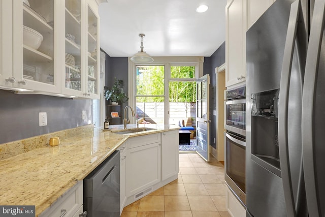 kitchen with light tile patterned flooring, a sink, stainless steel appliances, glass insert cabinets, and white cabinetry