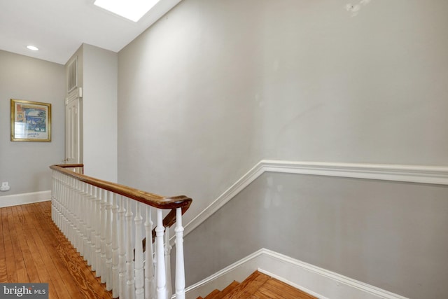 staircase featuring recessed lighting, a skylight, baseboards, and wood-type flooring