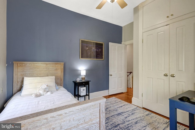 bedroom with a closet, ceiling fan, baseboards, and wood finished floors