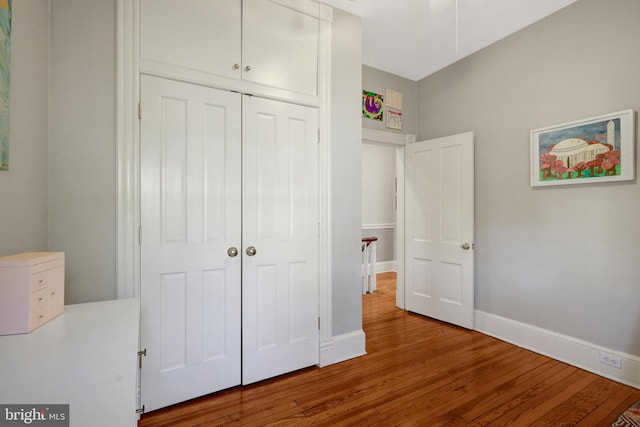 unfurnished bedroom featuring wood finished floors, a closet, and baseboards