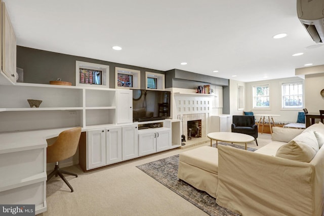 living area with recessed lighting, a fireplace with raised hearth, built in study area, and light colored carpet