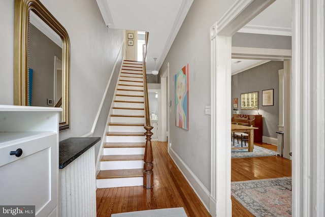 stairway featuring baseboards, wood finished floors, and ornamental molding