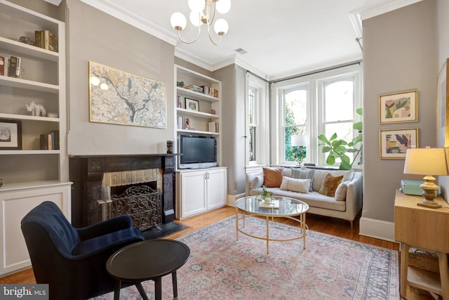 living area with a fireplace with flush hearth, ornamental molding, built in features, wood finished floors, and an inviting chandelier