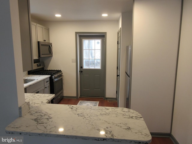 kitchen featuring white cabinetry, light stone countertops, stainless steel appliances, and kitchen peninsula