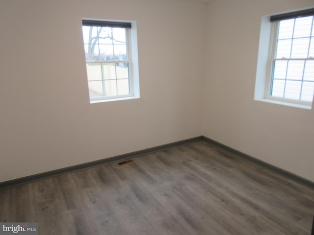 spare room with plenty of natural light and dark hardwood / wood-style flooring