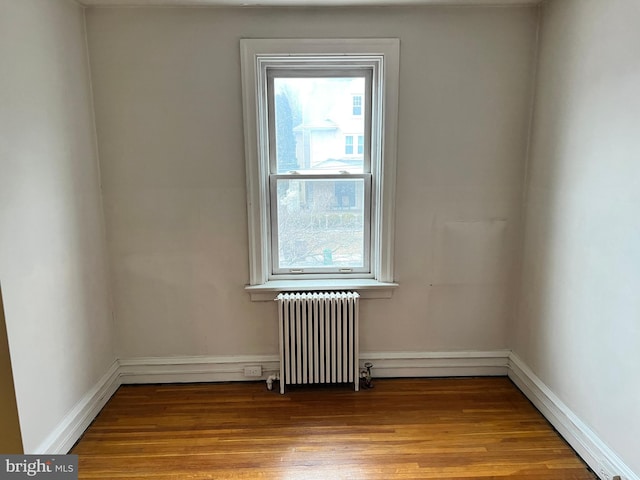 unfurnished room featuring a wealth of natural light, radiator heating unit, and light hardwood / wood-style floors