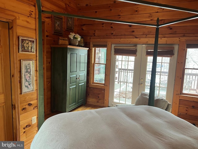 bedroom featuring access to outside, french doors, and wooden walls