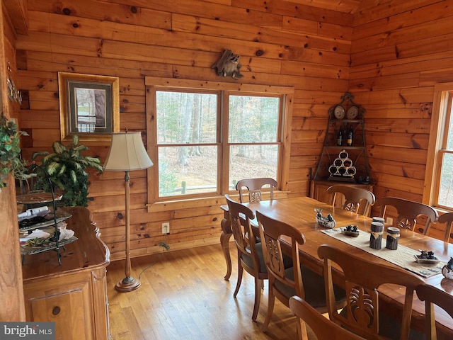 dining area featuring light wood-style floors and wooden walls