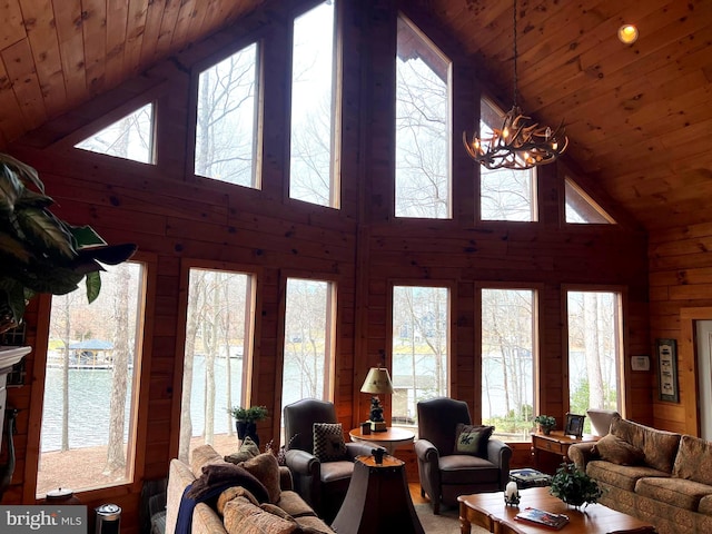 living room with wood ceiling, a water view, a notable chandelier, and wooden walls