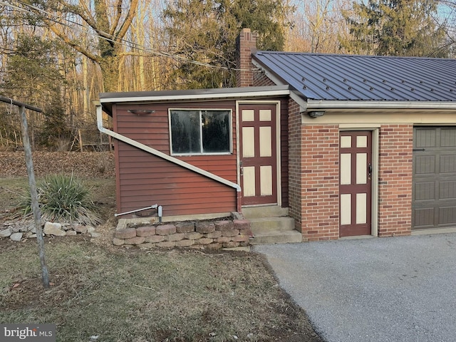 view of outdoor structure featuring entry steps, driveway, and a garage