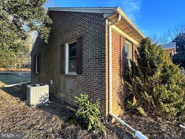 view of side of property with central AC unit and brick siding