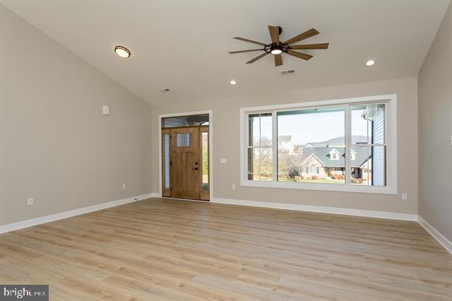 unfurnished living room with vaulted ceiling, ceiling fan, and light hardwood / wood-style floors