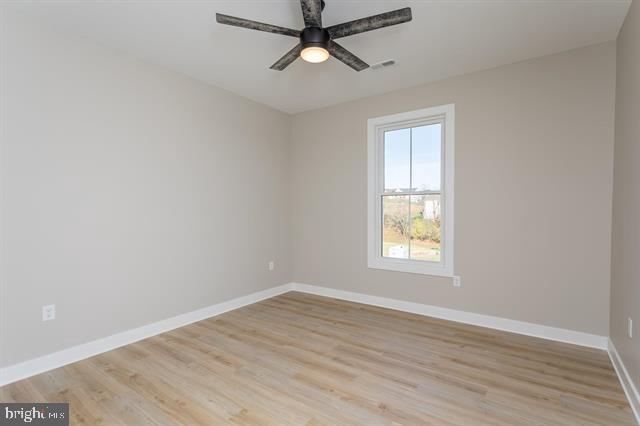 empty room with ceiling fan and light hardwood / wood-style floors