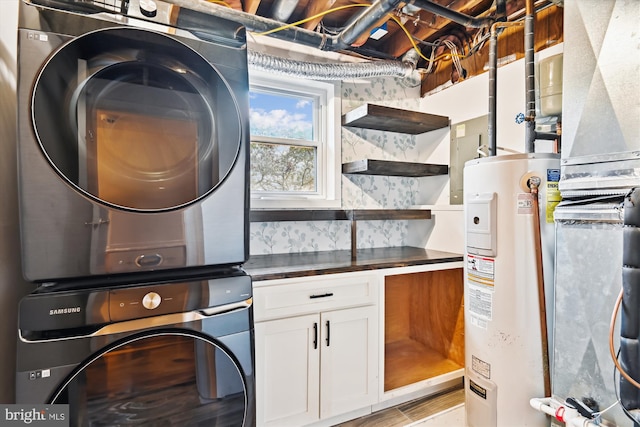 clothes washing area with cabinets, electric water heater, and stacked washing maching and dryer