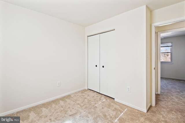 unfurnished bedroom with light carpet and a closet